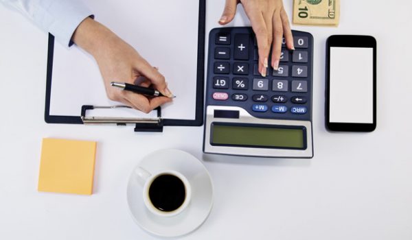 Calculating expenses Calculating expenses. High angle of young woman calculating invoice at desk. Woman counting money at the table